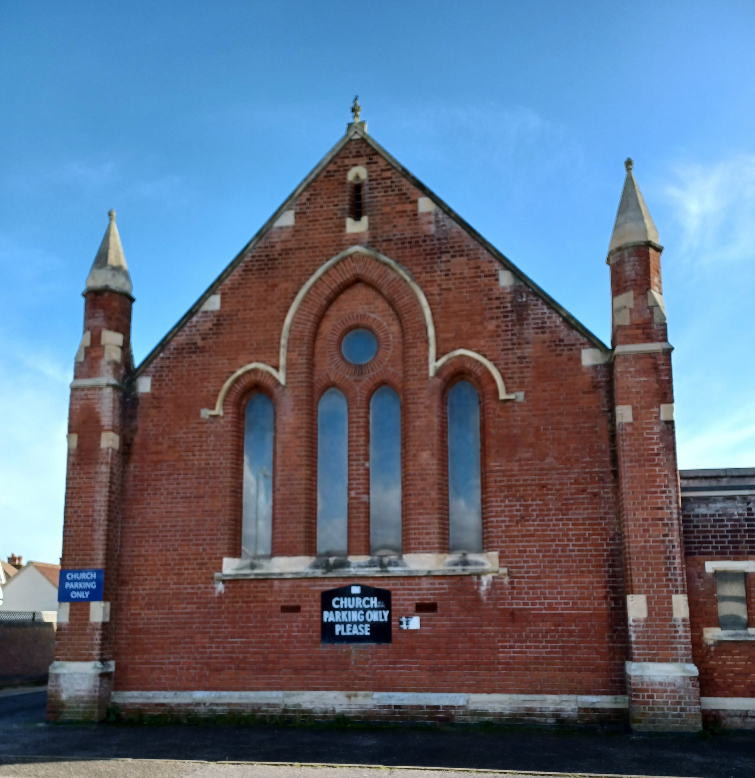 The end of a brick built church. Signs say CHURCH PARKING ONLY.