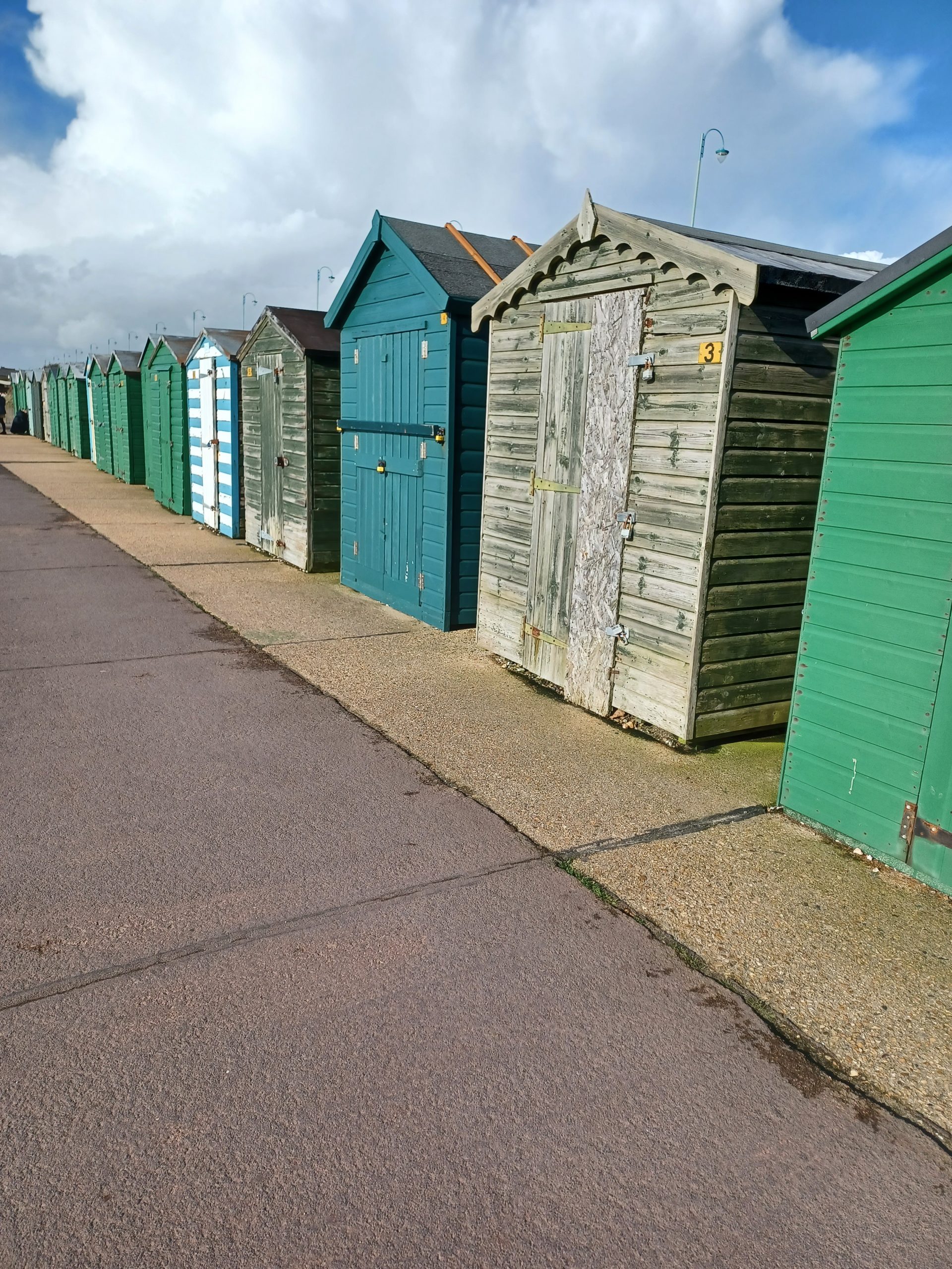 Several weather-worn beach huts in a row seen from the right